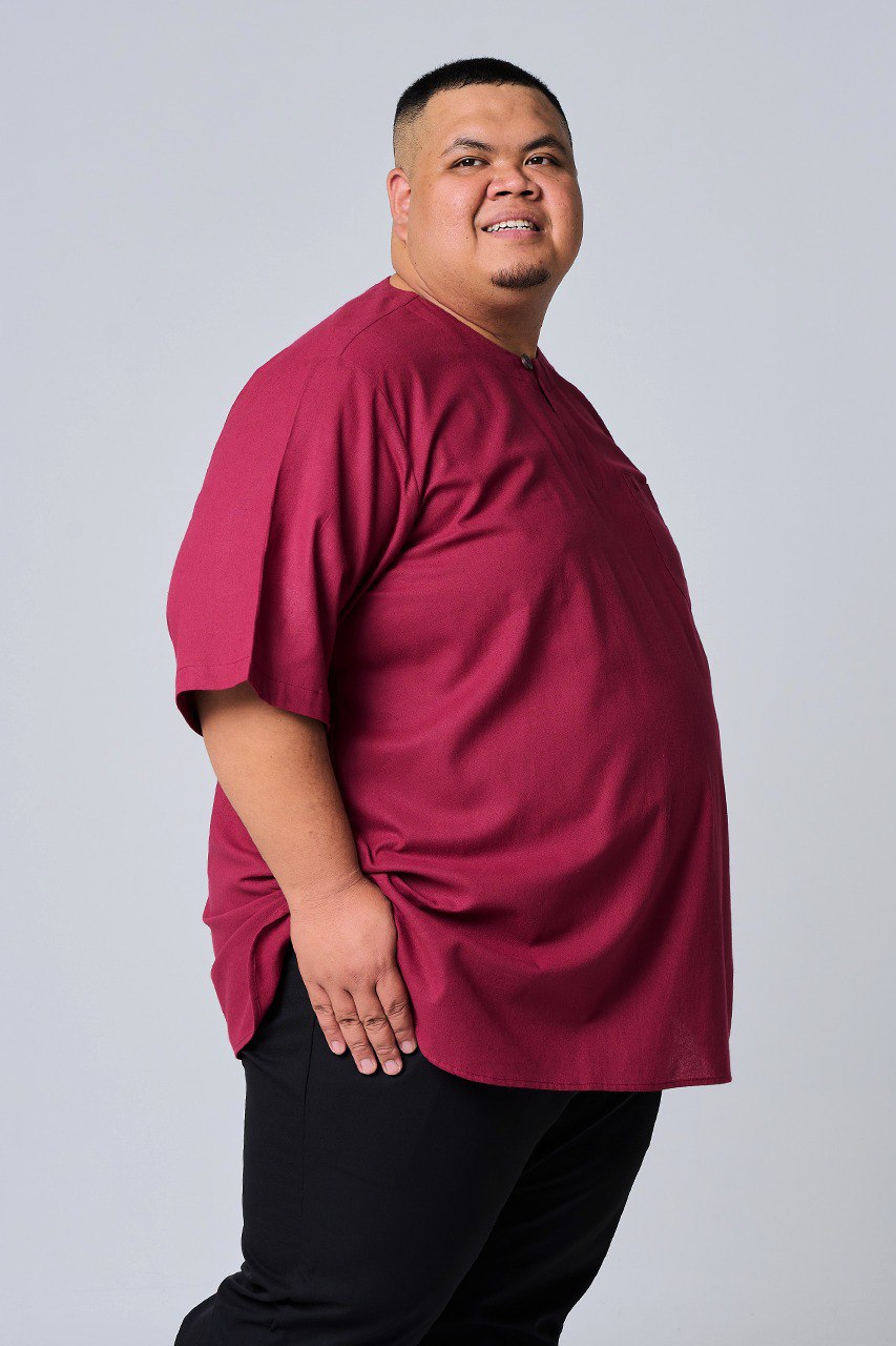 Person wearing a maroon shirt and black pants on a plain background #color_maroon