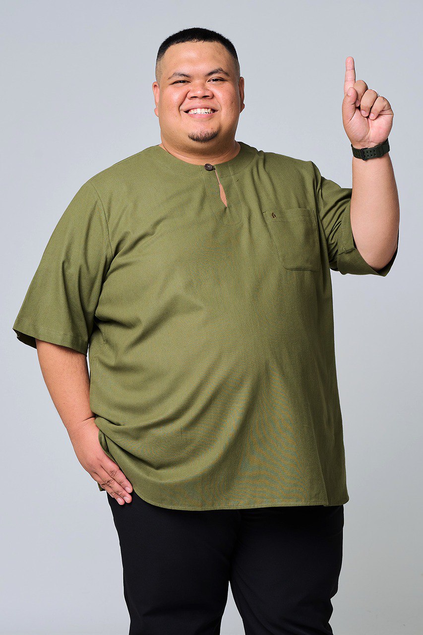 Man wearing an olive green shirt and black pants against a gray background #color_olive green