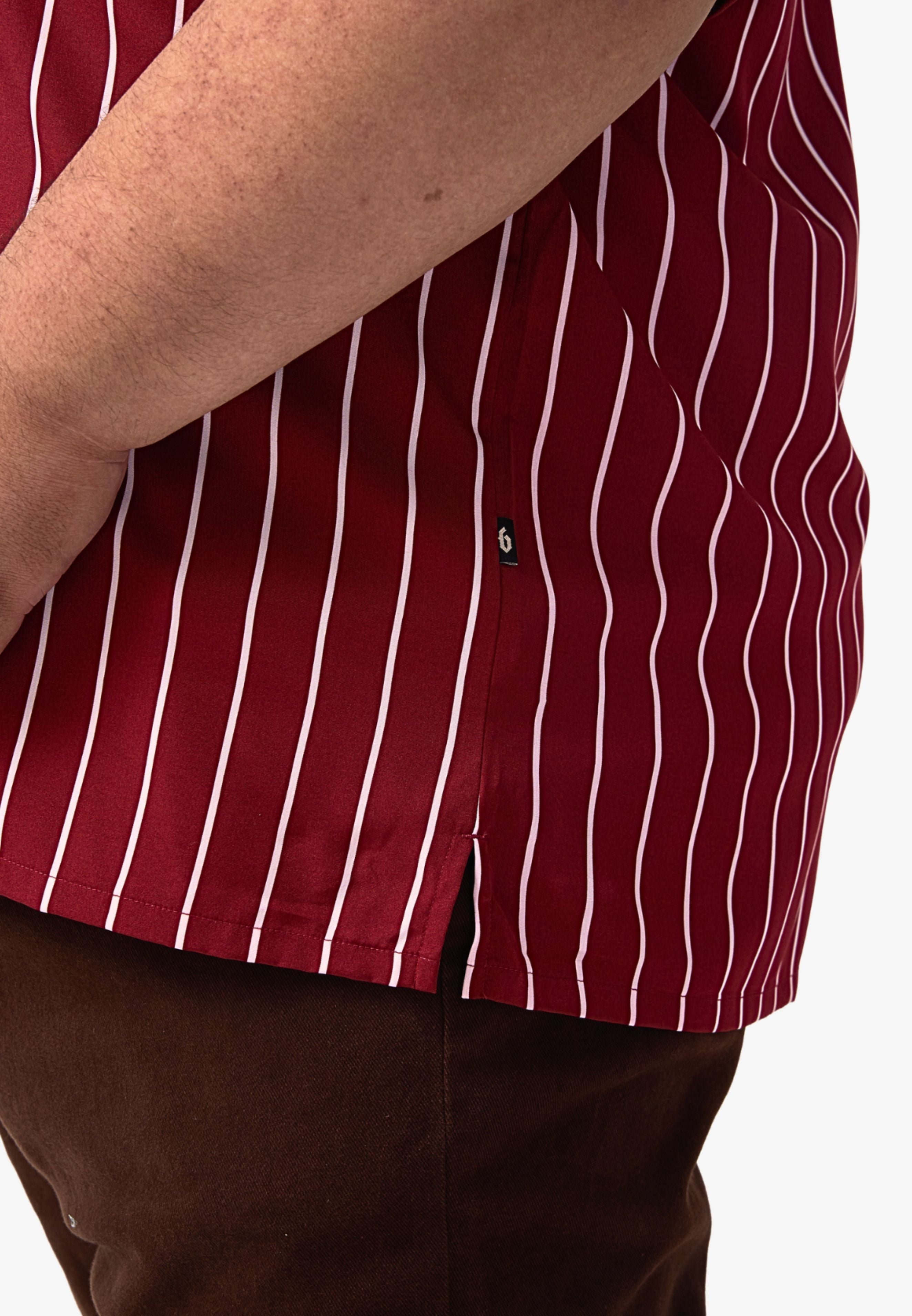 A close-up of the slit with a 'B' flag tag logo on a maroon shirt with white stripes. #color_maroon