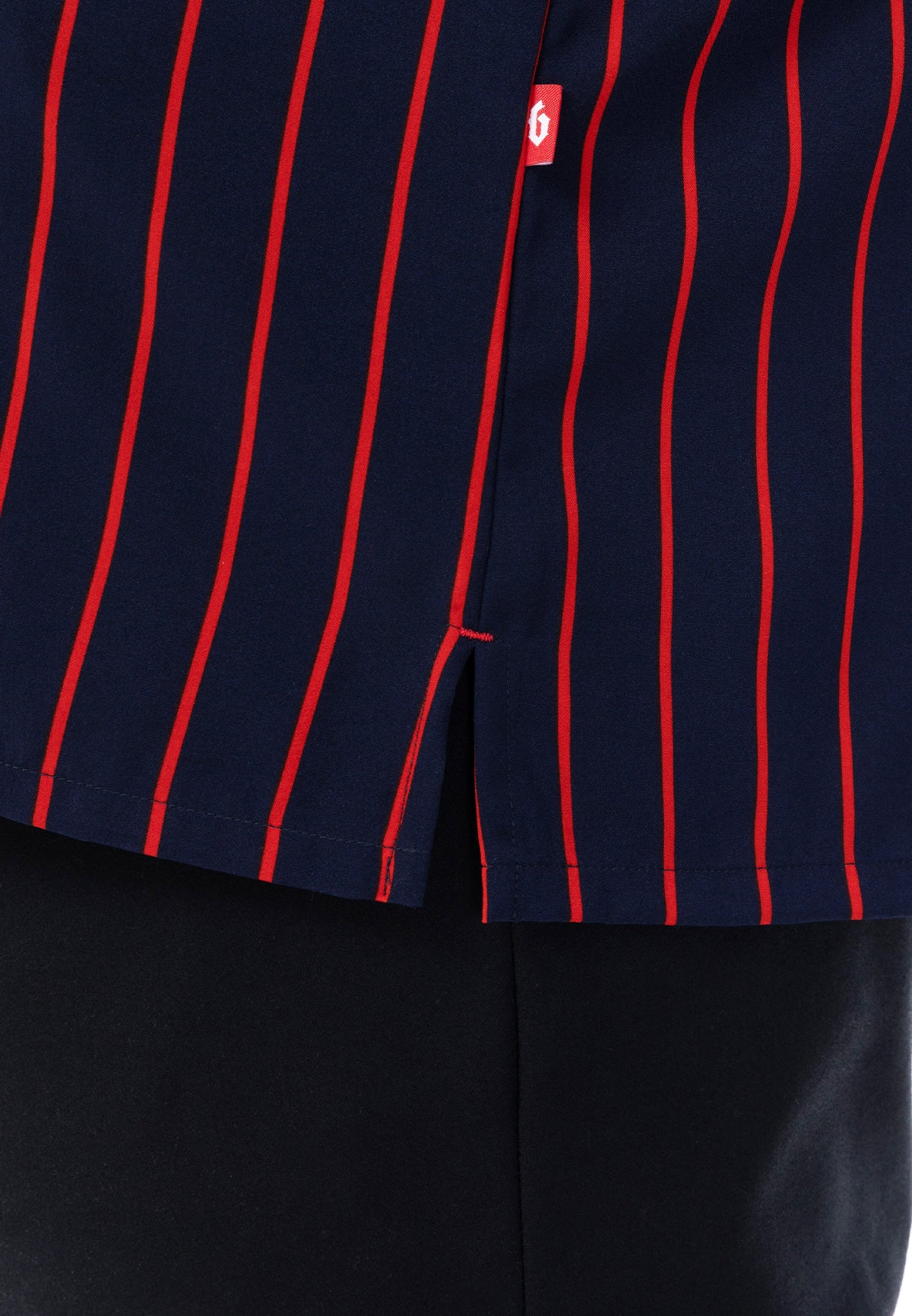 A close-up of the slit with a 'B' flag tag logo on a navy blue shirt with red stripes. #color_navy blue